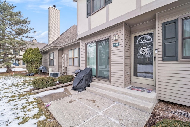 snow covered property entrance featuring a patio