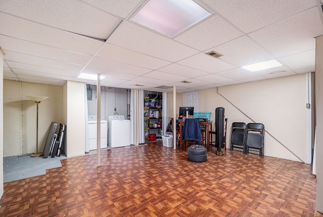 basement featuring a paneled ceiling, parquet floors, and washer and clothes dryer