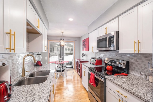 kitchen featuring white cabinetry, appliances with stainless steel finishes, pendant lighting, and light stone counters