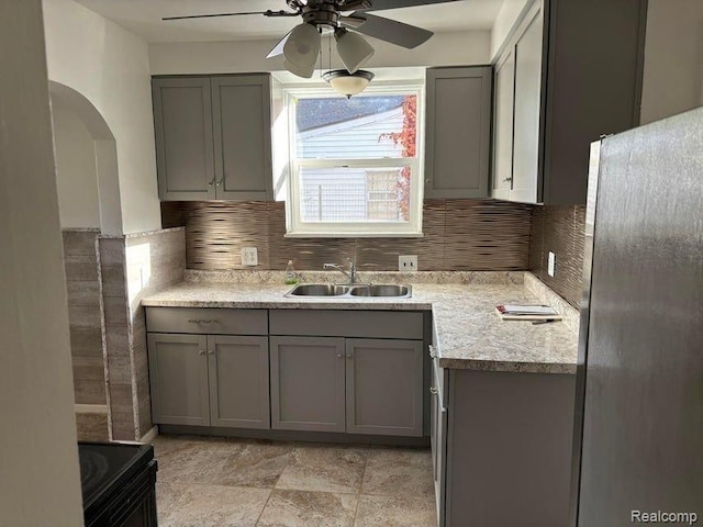 kitchen featuring sink, gray cabinetry, stainless steel fridge, backsplash, and black / electric stove