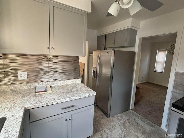 kitchen featuring gray cabinetry, light stone counters, light carpet, appliances with stainless steel finishes, and ceiling fan