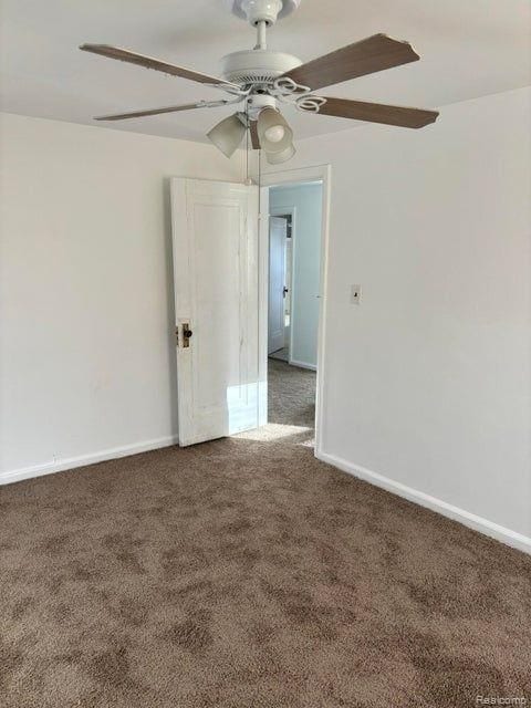 empty room with ceiling fan and dark carpet