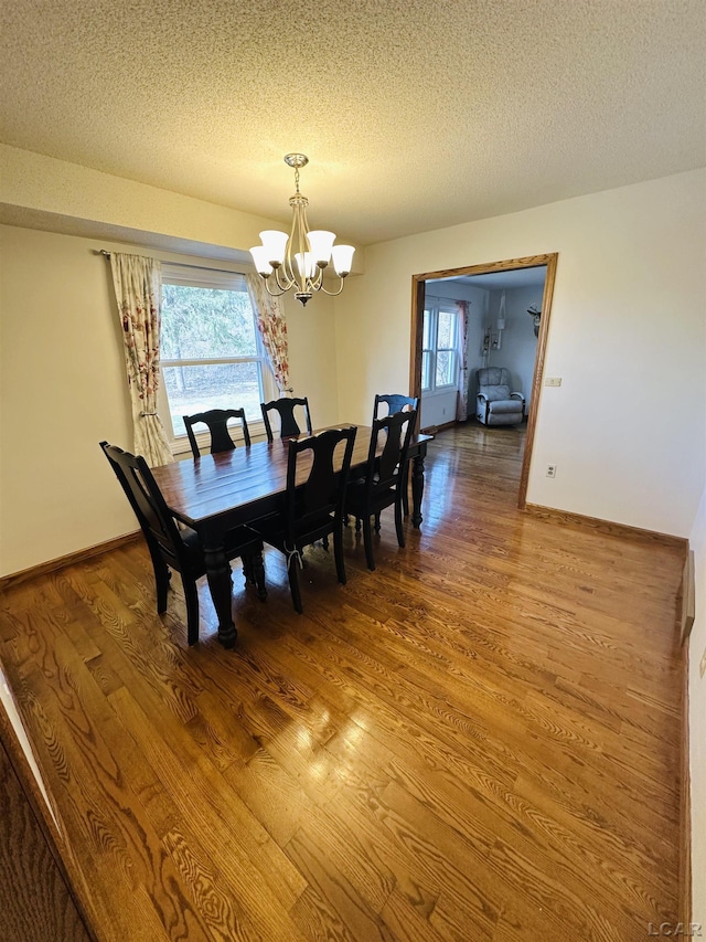 dining space with an inviting chandelier, hardwood / wood-style floors, and a textured ceiling