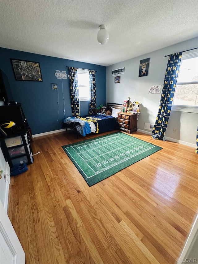 bedroom featuring multiple windows, hardwood / wood-style flooring, and a textured ceiling