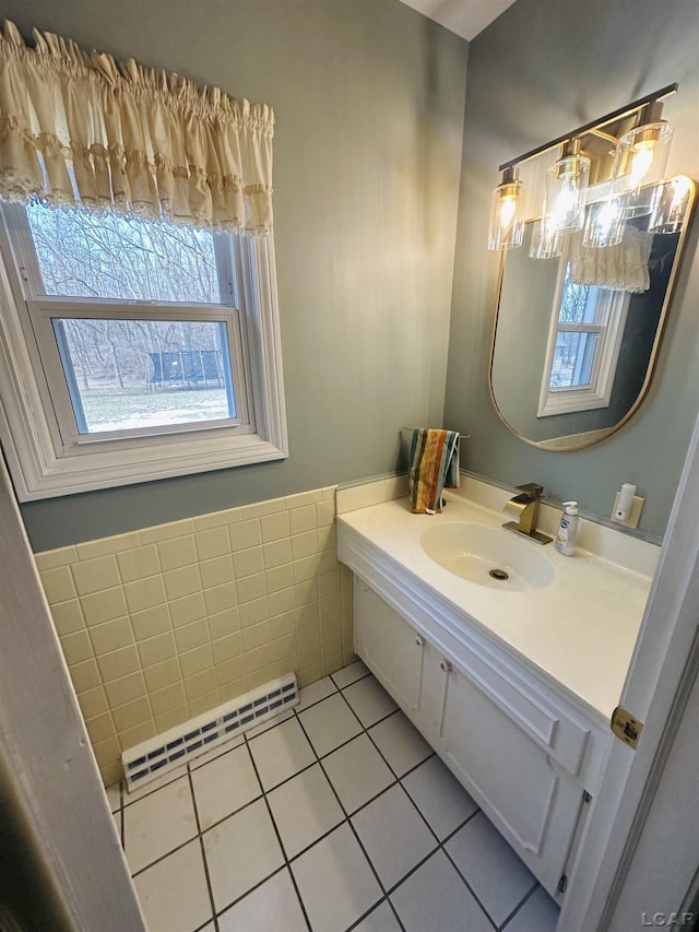 bathroom with baseboard heating, tile patterned floors, vanity, and tile walls