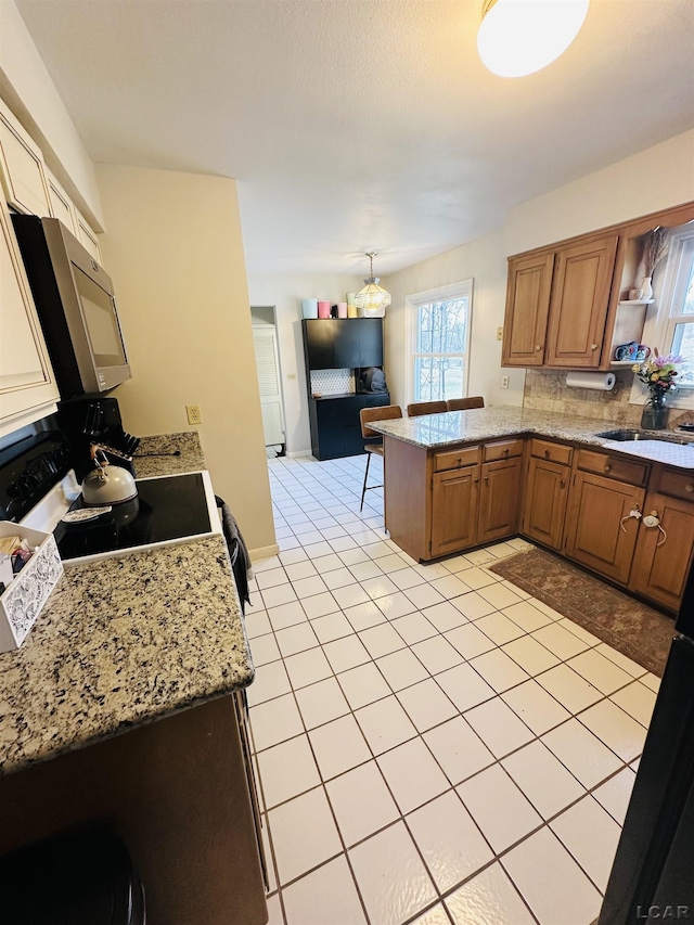 kitchen with range with electric stovetop, sink, backsplash, light tile patterned floors, and kitchen peninsula