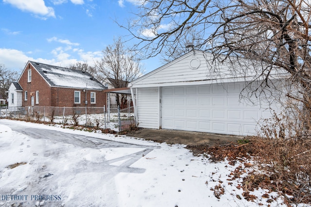 snow covered property featuring an outbuilding and a garage