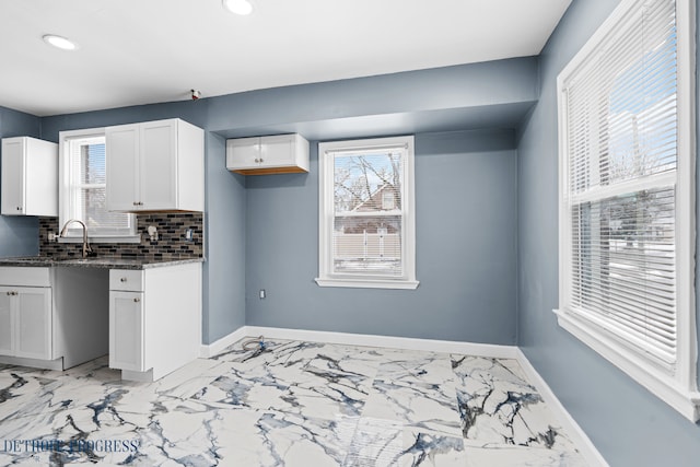 kitchen with white cabinetry, sink, dark stone countertops, and backsplash