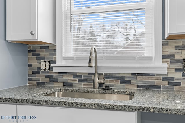 kitchen with sink, white cabinets, light stone counters, and decorative backsplash