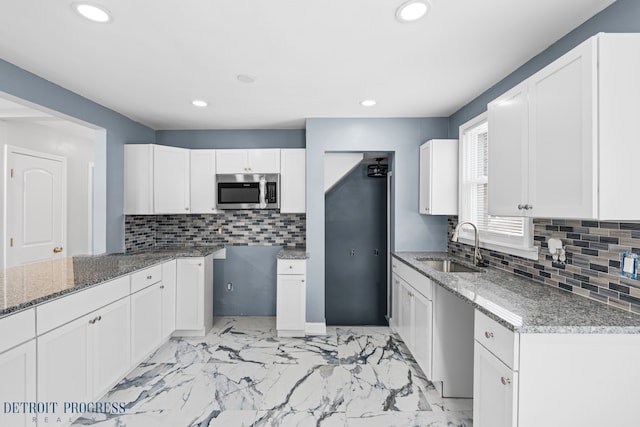 kitchen featuring white cabinetry, dark stone counters, sink, and tasteful backsplash