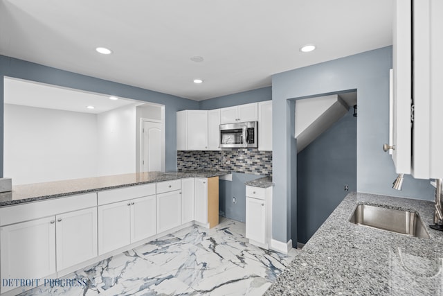 kitchen featuring sink, backsplash, white cabinets, and stone counters