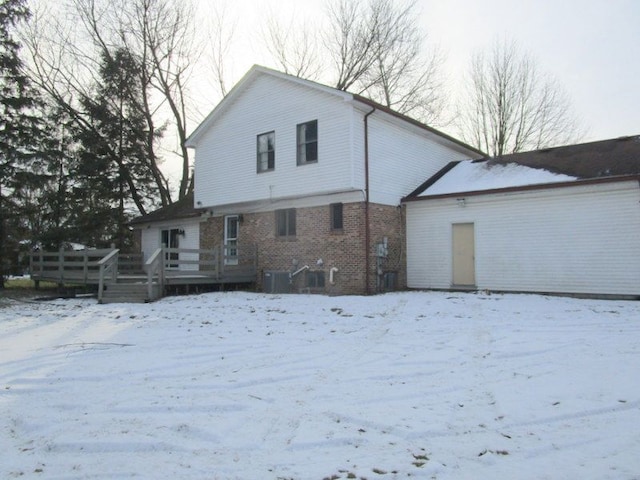 snow covered house with a wooden deck and central AC