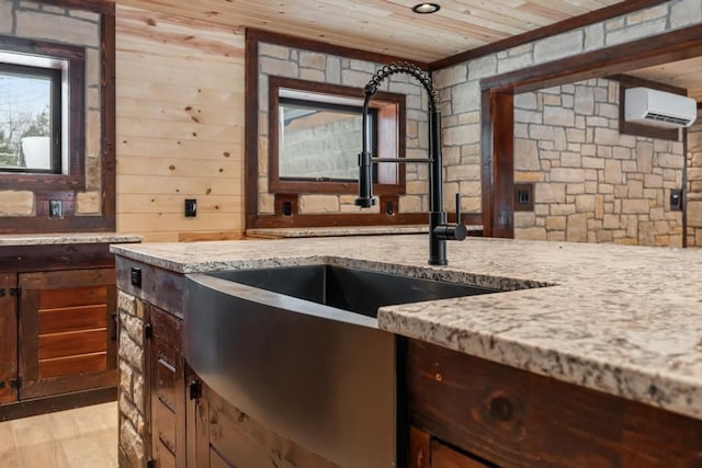 kitchen with sink, a wall mounted AC, light stone counters, light hardwood / wood-style floors, and wooden ceiling