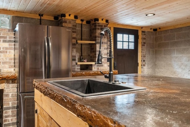 kitchen with sink, stainless steel fridge, brick wall, light brown cabinetry, and wooden ceiling