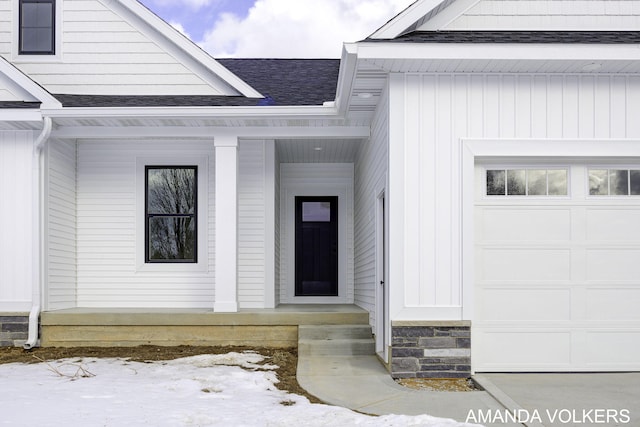 snow covered property entrance with a garage