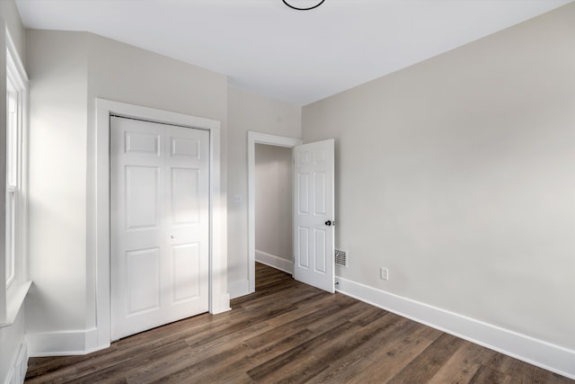 unfurnished bedroom with dark wood-type flooring and a closet