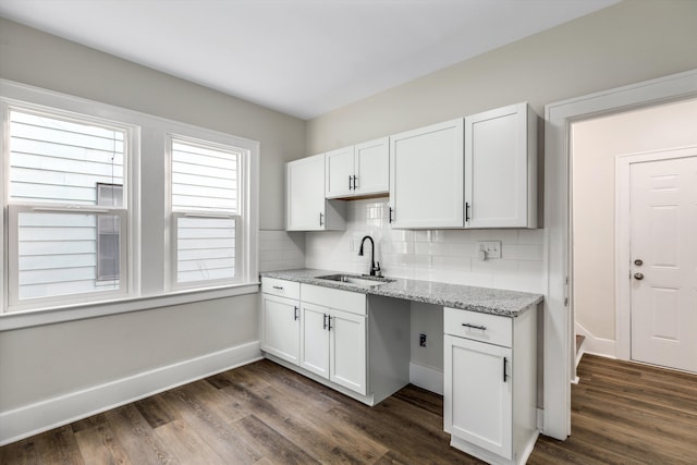 kitchen with sink, white cabinetry, light stone counters, dark hardwood / wood-style floors, and decorative backsplash