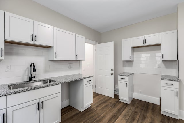 kitchen with sink, backsplash, dark hardwood / wood-style floors, light stone countertops, and white cabinets