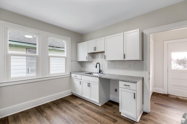 kitchen with dark hardwood / wood-style floors, light stone countertops, sink, and white cabinets