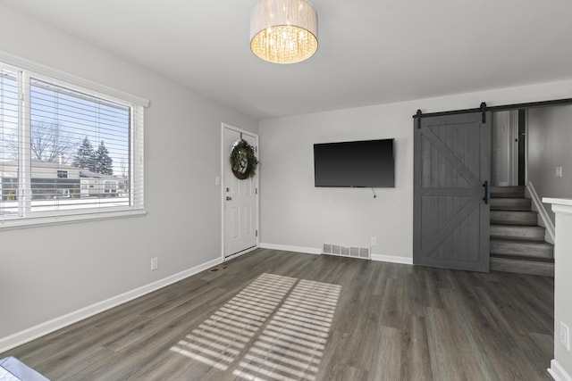 entryway featuring a barn door, dark hardwood / wood-style flooring, and a notable chandelier