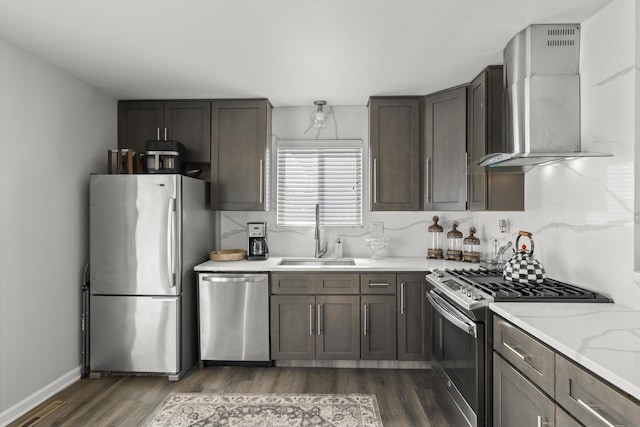 kitchen with sink, light stone counters, stainless steel appliances, dark wood-type flooring, and wall chimney exhaust hood