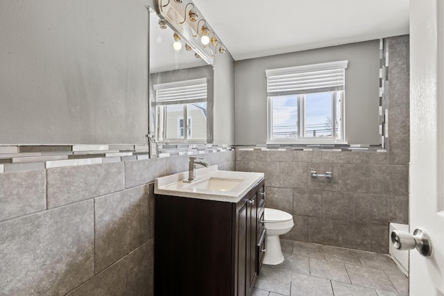 bathroom featuring vanity, tile patterned flooring, tile walls, and toilet