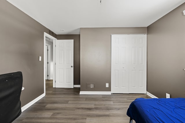 bedroom with dark hardwood / wood-style flooring and a closet