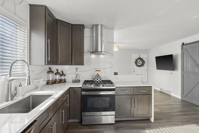 kitchen featuring sink, gas stove, ventilation hood, dark hardwood / wood-style floors, and a barn door