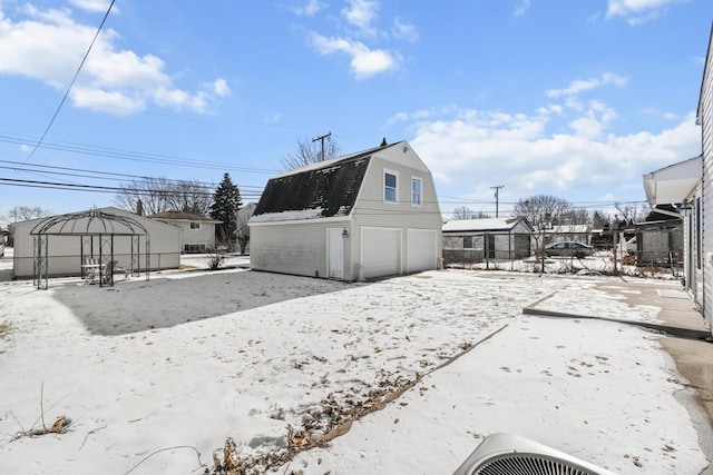 snow covered rear of property with a garage, an outdoor structure, and central air condition unit