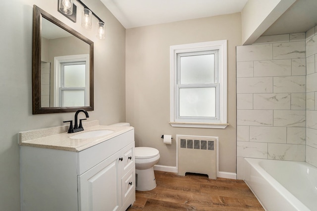 bathroom featuring vanity, hardwood / wood-style floors, radiator heating unit, and a healthy amount of sunlight