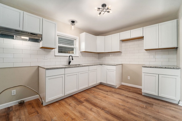 kitchen featuring tasteful backsplash, light wood-type flooring, sink, and white cabinets