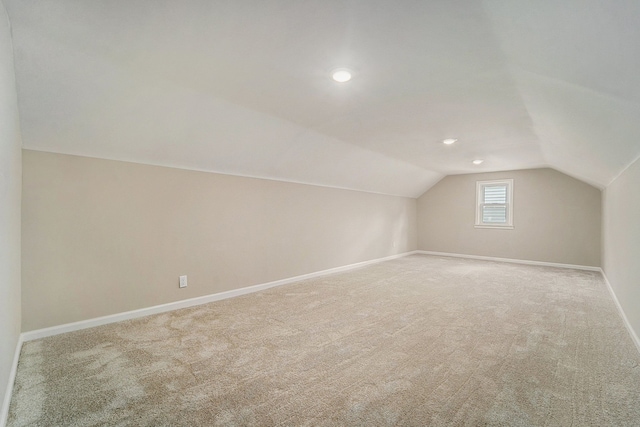 bonus room featuring vaulted ceiling and light colored carpet