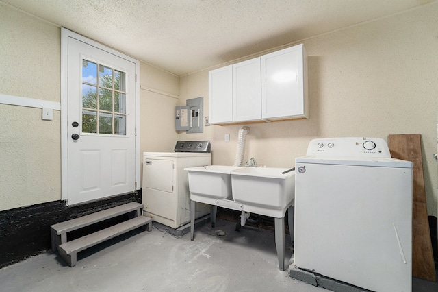 laundry room featuring a textured ceiling, electric panel, cabinets, and washing machine and clothes dryer