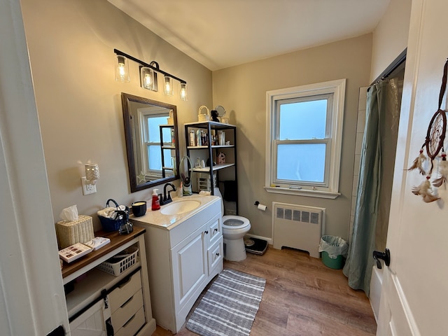 bathroom featuring toilet, a shower with curtain, radiator heating unit, vanity, and hardwood / wood-style floors