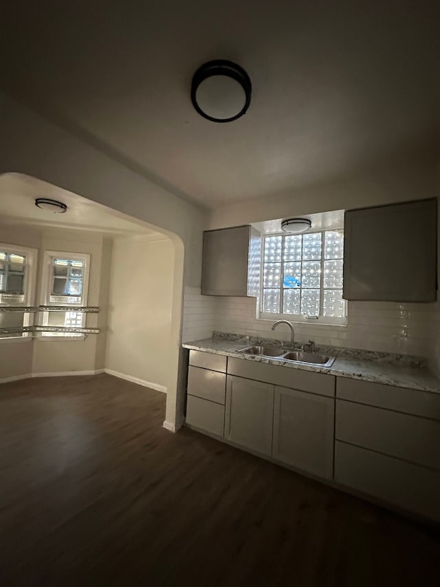 kitchen featuring dark hardwood / wood-style floors, sink, gray cabinetry, decorative backsplash, and light stone countertops