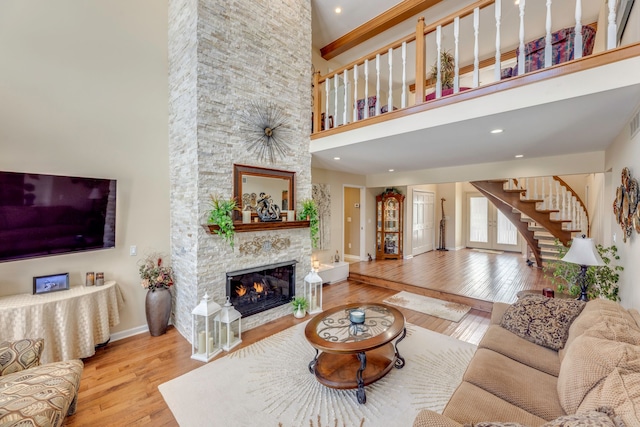 living room featuring a high ceiling, a fireplace, and light wood-type flooring