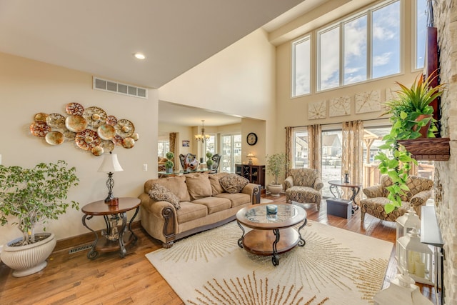 living room with a high ceiling, a chandelier, and light wood-type flooring