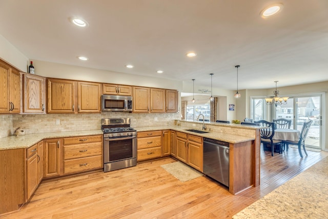 kitchen featuring hanging light fixtures, appliances with stainless steel finishes, sink, and kitchen peninsula