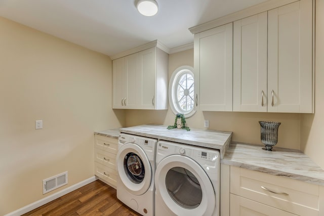 clothes washing area featuring dark wood-type flooring, cabinets, and washing machine and clothes dryer