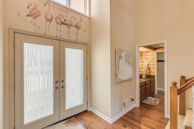 foyer entrance with a high ceiling, light hardwood / wood-style flooring, and french doors