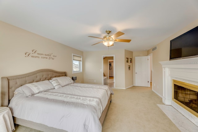 bedroom featuring a fireplace, light colored carpet, and ceiling fan