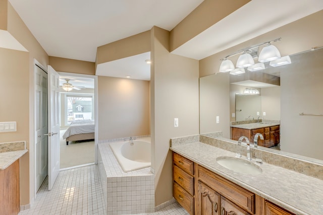 bathroom featuring tiled tub, vanity, and tile patterned floors