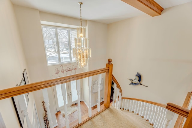 staircase featuring beamed ceiling, carpet floors, and a chandelier