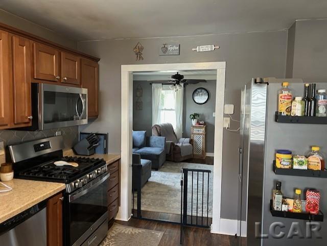 kitchen featuring ceiling fan, appliances with stainless steel finishes, dark hardwood / wood-style flooring, and decorative backsplash