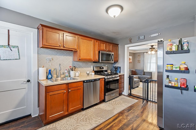 kitchen featuring sink, ceiling fan, backsplash, stainless steel appliances, and dark hardwood / wood-style flooring