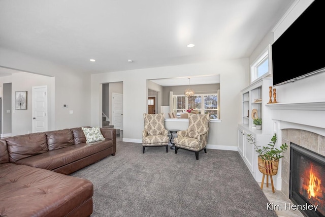 carpeted living room featuring a tiled fireplace and a chandelier