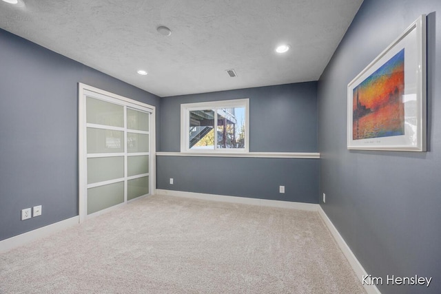 spare room featuring a textured ceiling and carpet