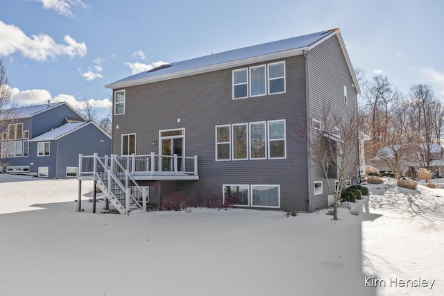 snow covered house featuring a wooden deck