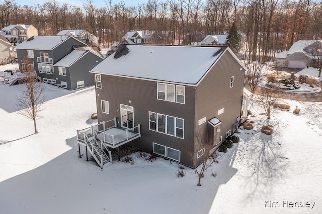 snow covered rear of property with a wooden deck