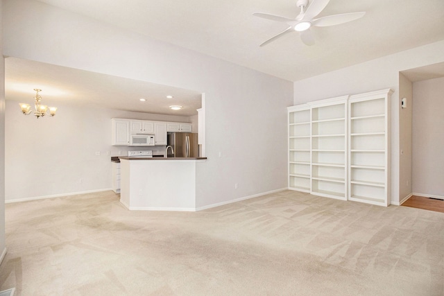 unfurnished living room with ceiling fan with notable chandelier and light colored carpet